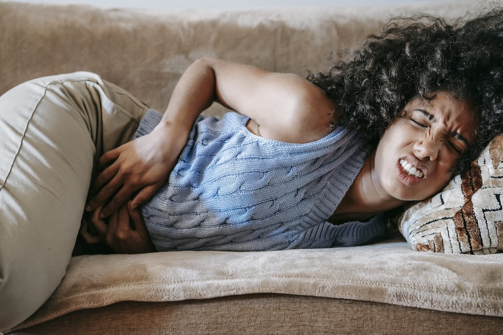 Woman Suffering from a Stomach Pain Lying Down on Couch